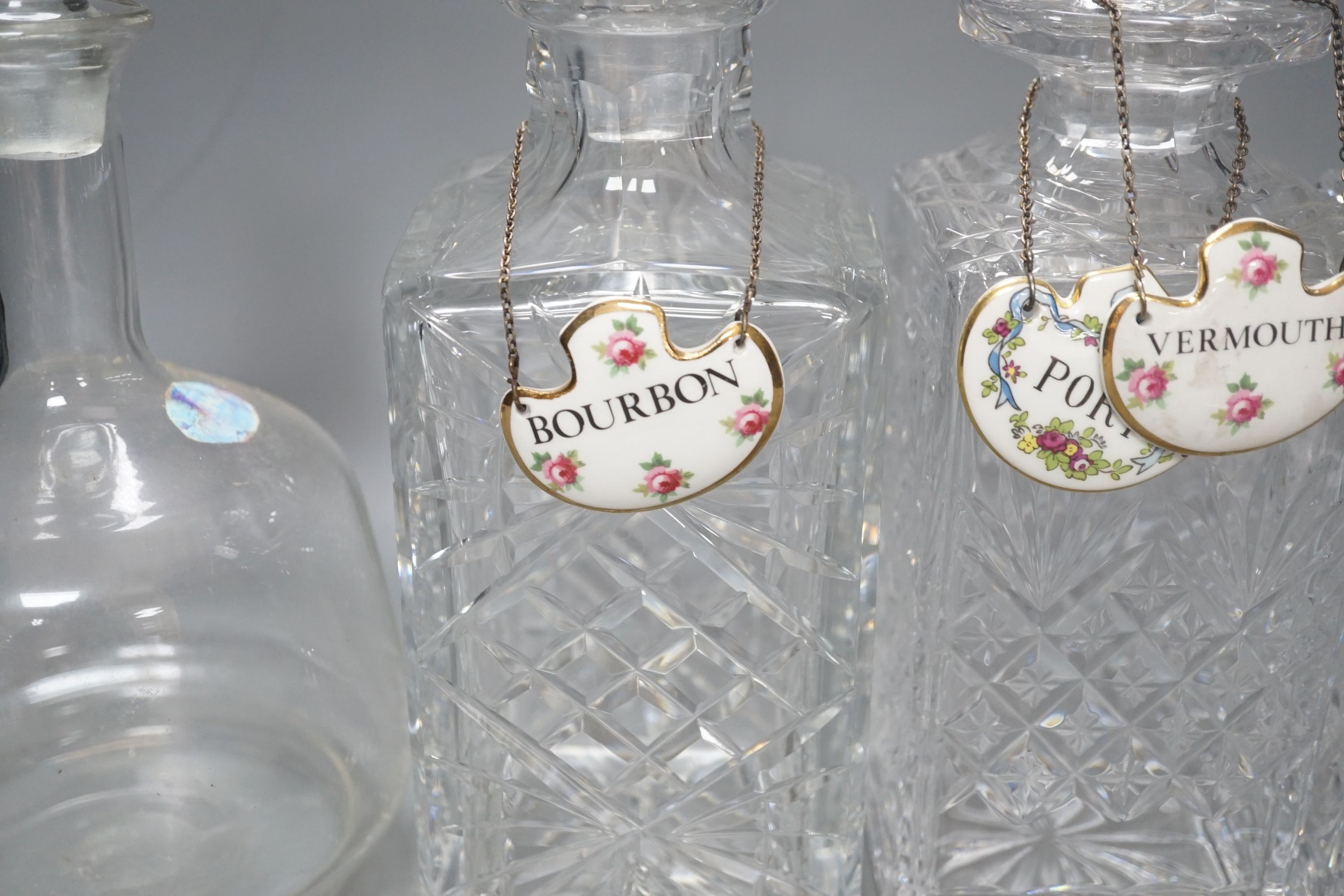 A pair of glass decanters, another similar and a mallet decanter and four decanter labels, Pair 27 cms high.